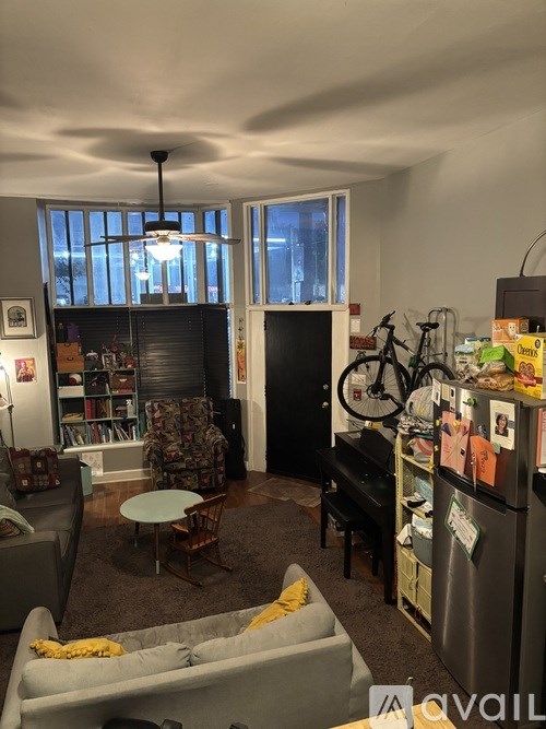 A living room with a grey sofa, a black piano, and a bicycle on the wall.