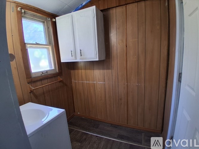 A small bathroom with a toilet, sink, and wooden walls.