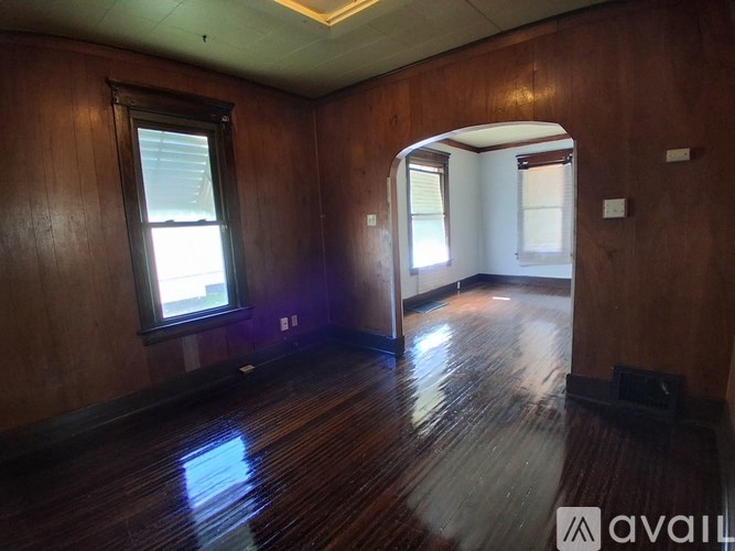 A room with wooden floors and walls, a window, and a door.