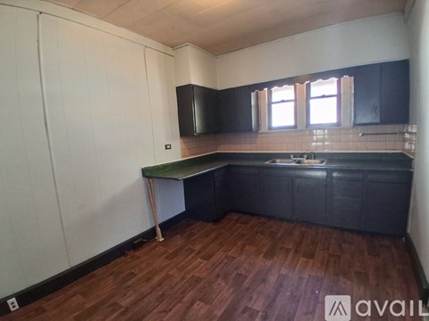 A kitchen with black cabinets and a wooden floor.