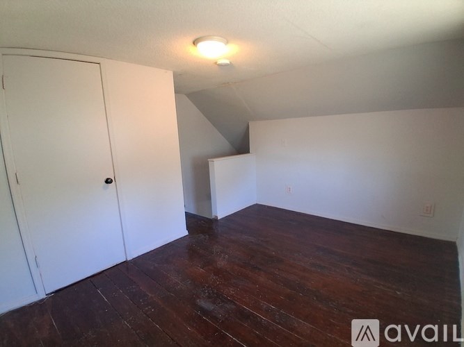 A room with a white door and wooden floor.