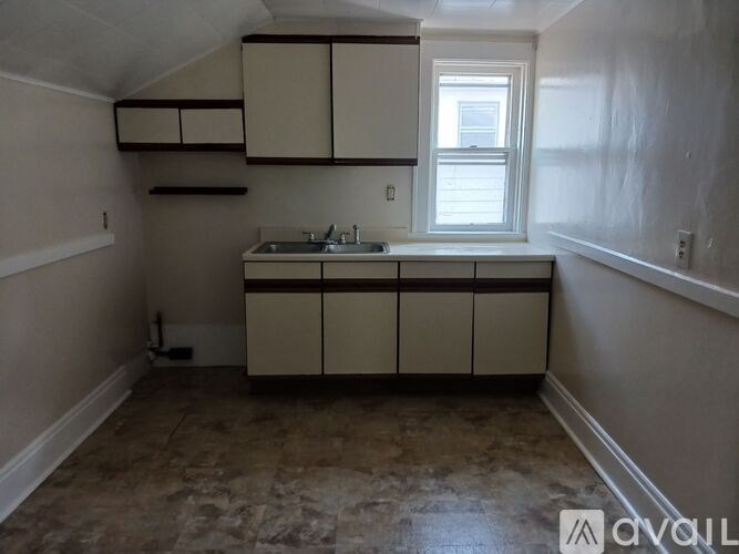A kitchen with beige cabinets and a window.