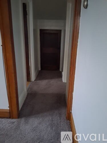 A hallway with a carpeted floor and white walls.