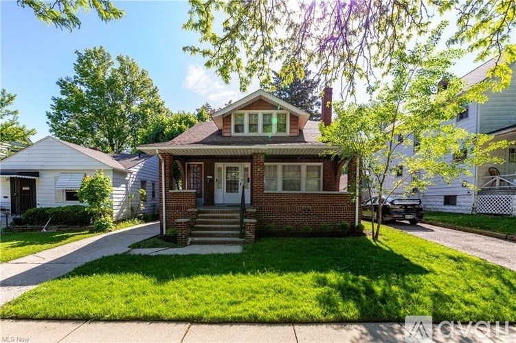 A house with a brick facade and a white fence in the background.