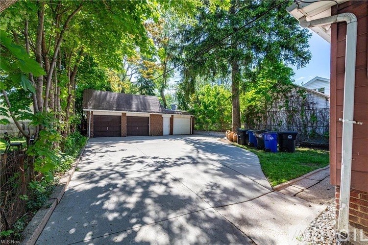 A residential driveway with a garage and trees.