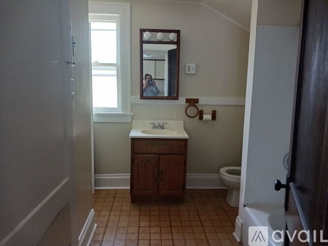 A bathroom with a toilet, sink, and a mirror.