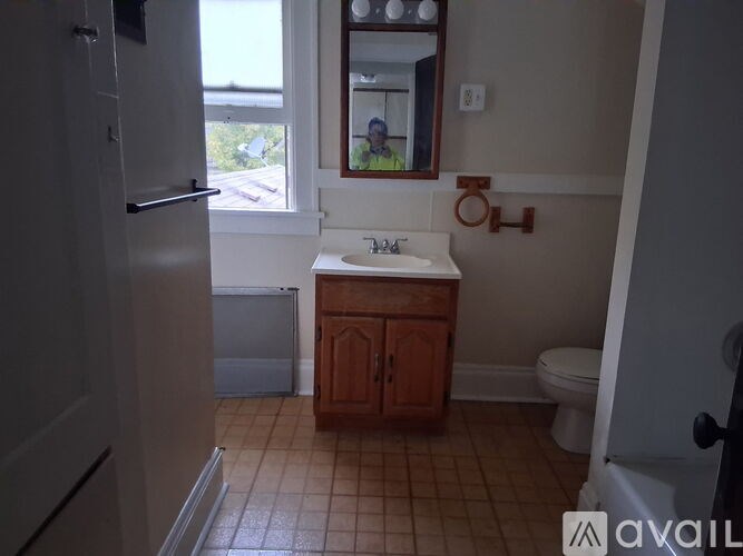 A bathroom with a toilet, sink, and a window.