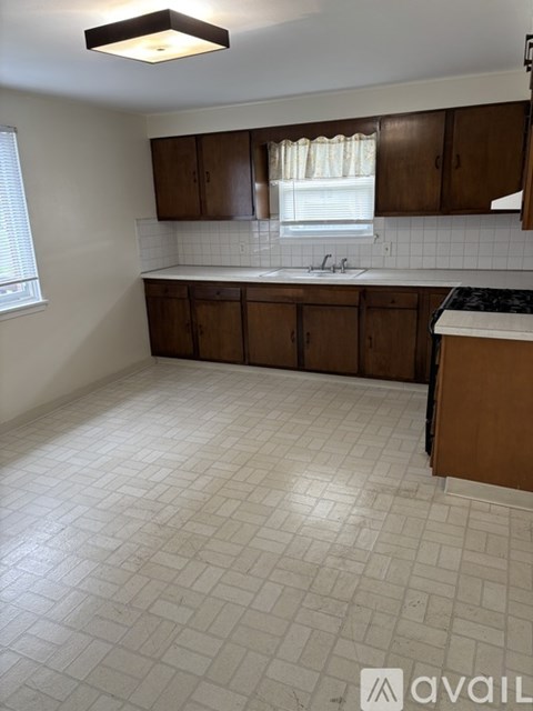 A kitchen with white tiled floors and wooden cabinets.