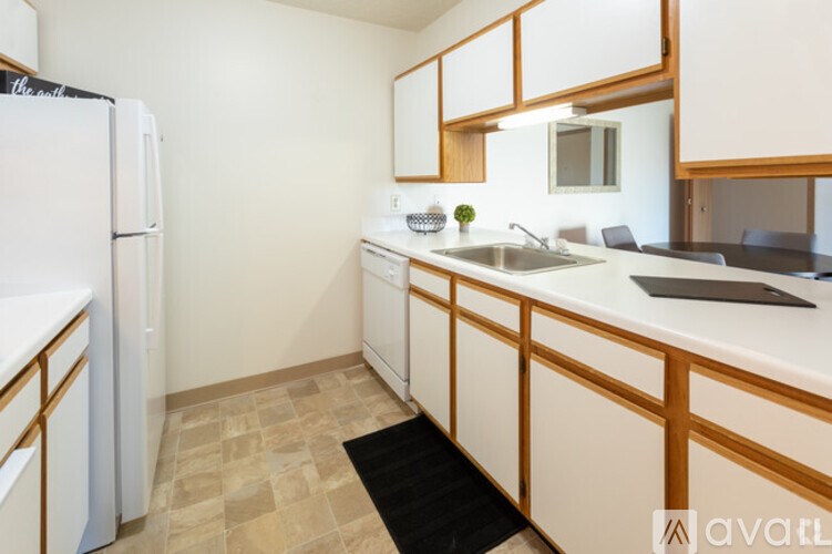 A kitchen with wooden cabinets and a black mat on the floor.