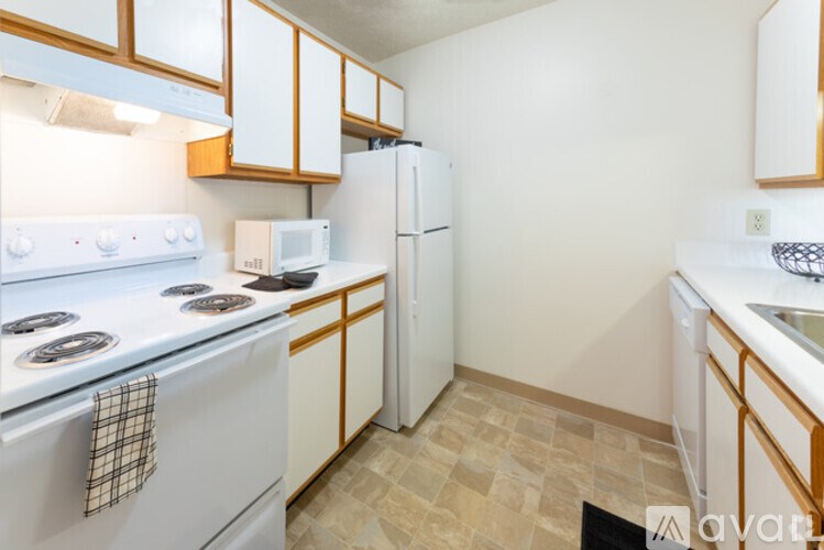 A kitchen with white appliances and wooden cabinets.
