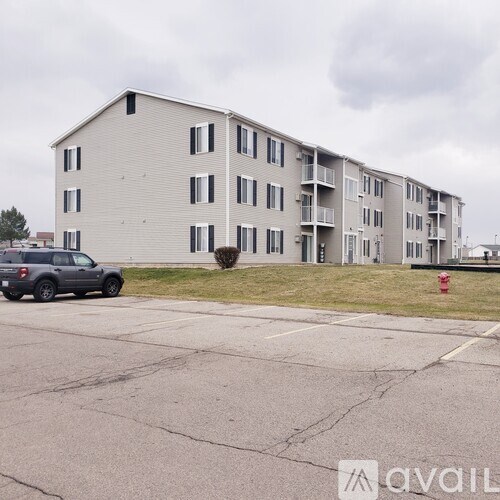 A grey apartment building with a red fire hydrant in front of it.