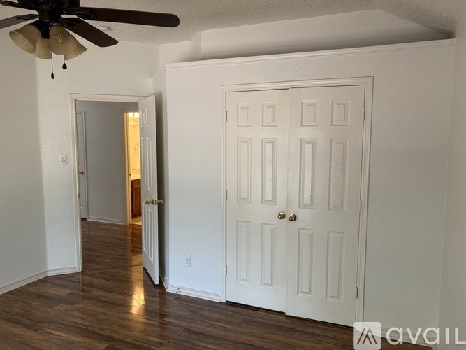 A room with a white door and a ceiling fan.
