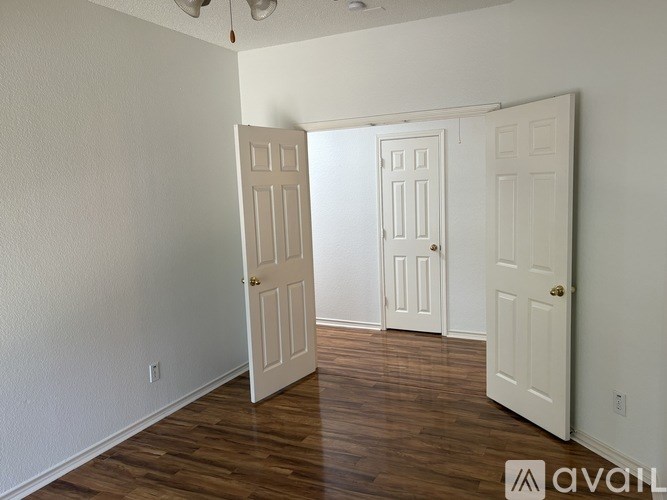 Three white doors in a room with wood floors.