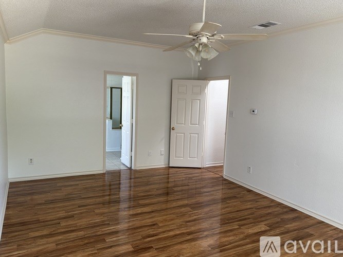 A room with a ceiling fan and wooden floors.