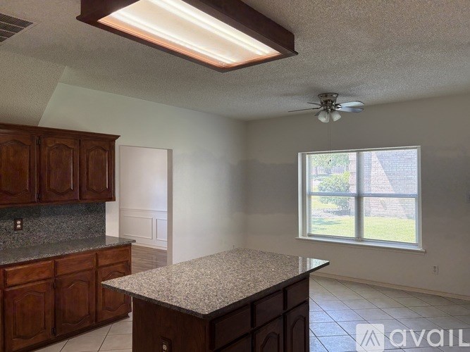 A kitchen with granite countertops and wooden cabinets is available for rent.