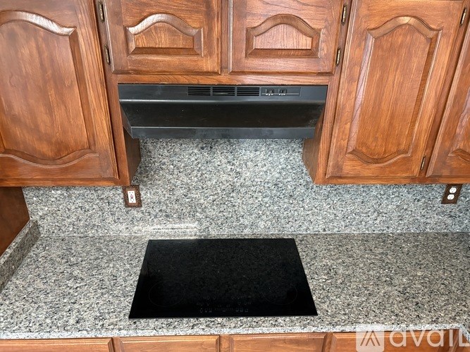 A black mat is on the floor under a cabinet.