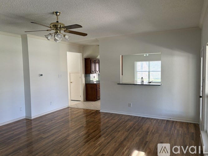 A room with a ceiling fan and wooden floors.