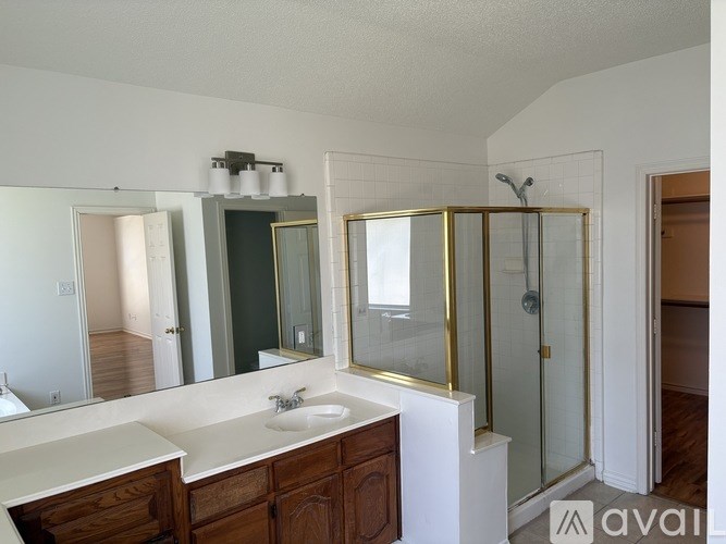 A bathroom with a sink, mirror, and shower.