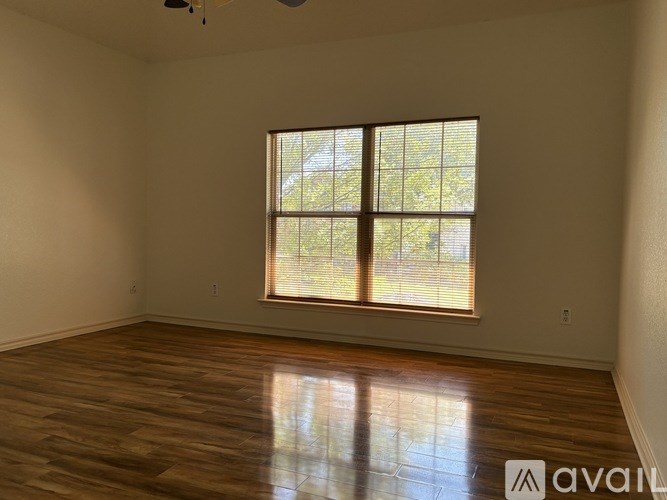 A room with wooden flooring and a window with blinds.