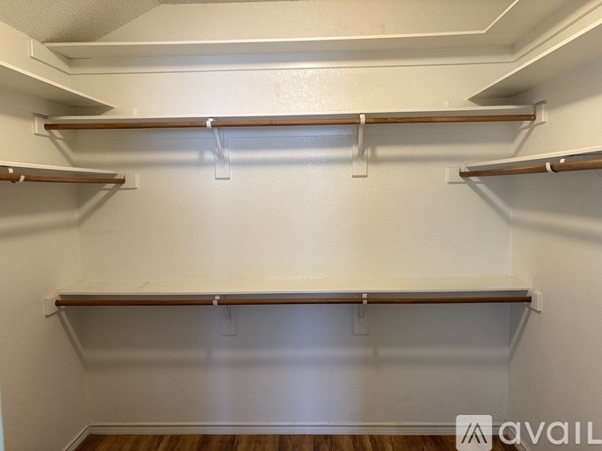 Empty pantry with white walls and wooden shelves.