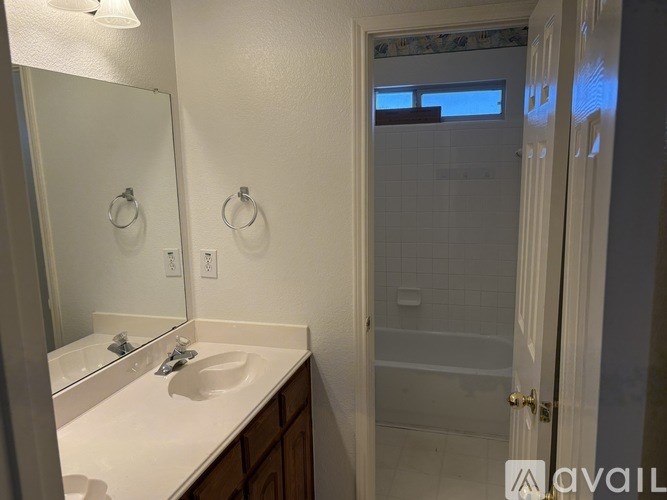 A bathroom with a sink, mirror, and shower.