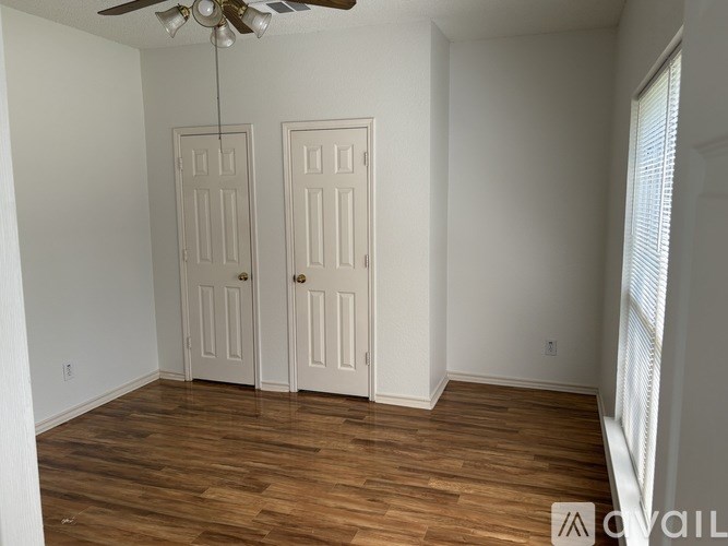 A room with a ceiling fan and two doors.