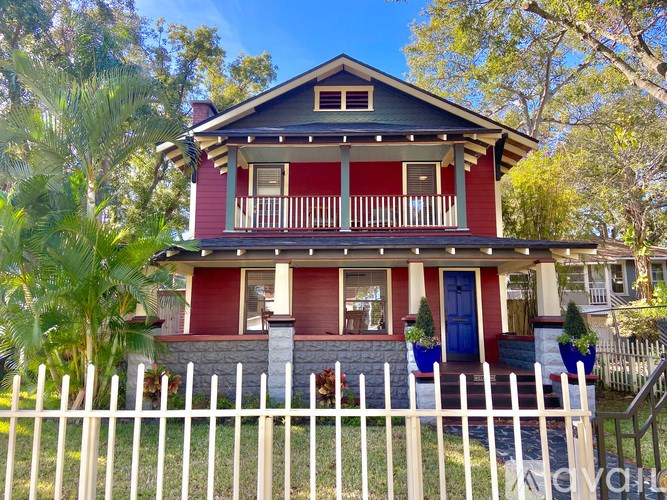 A red house with a white picket fence in front.