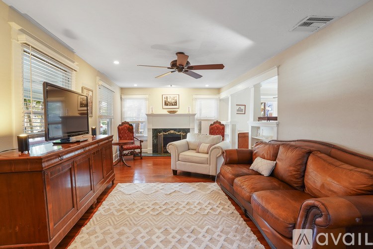 A living room with a brown leather couch and a wooden cabinet.