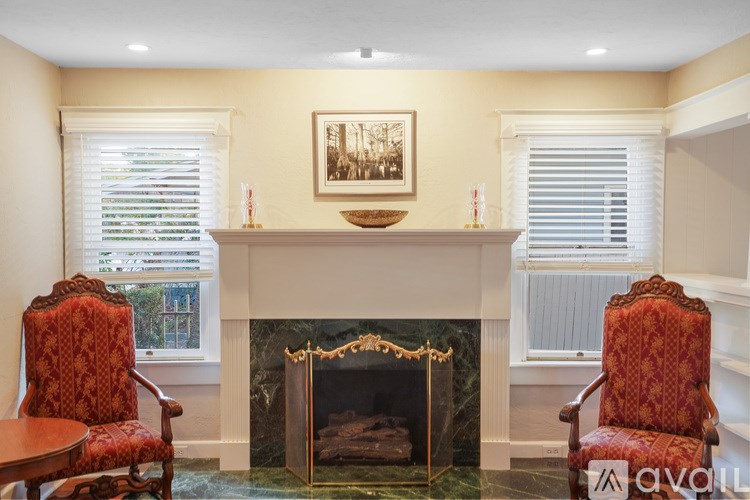 A living room with a fireplace and two chairs.