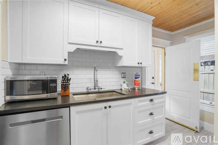 A kitchen with white cabinets and a wooden ceiling.