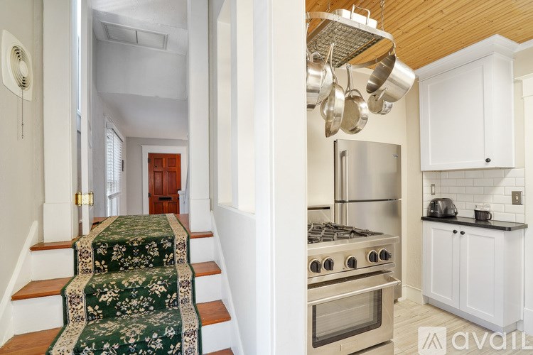 A kitchen with a stove and a staircase with a green carpet.