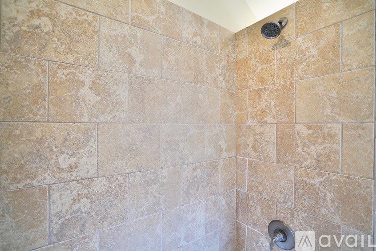A shower with a tiled wall and a shower head.