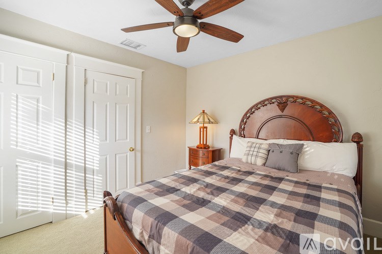 A bedroom with a bed, a ceiling fan, and a lamp.