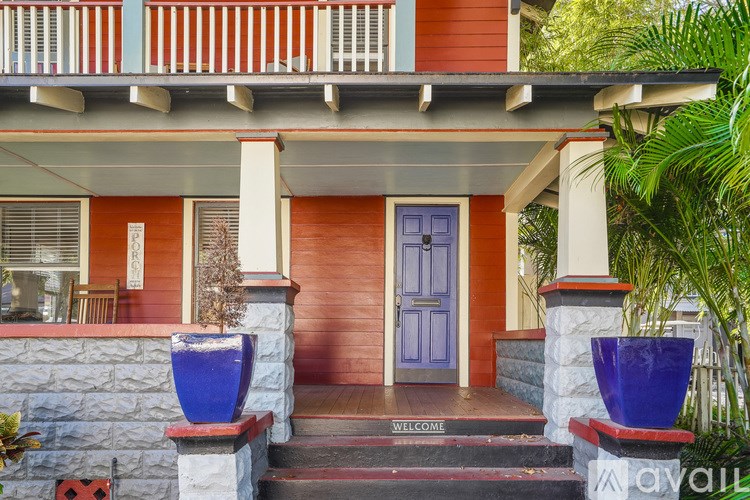 A red house with a blue door and a welcome mat.