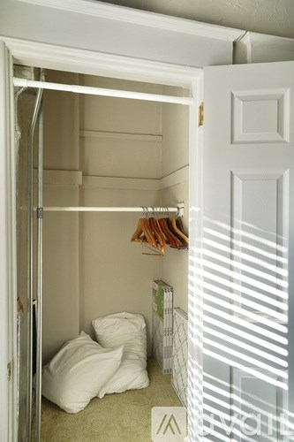 A white door is open to a room with a bed and a rack of clothes.