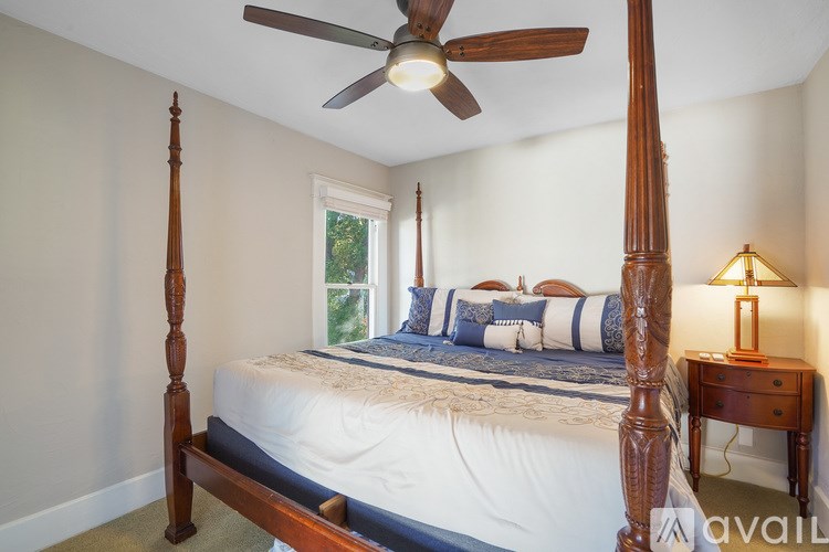 A bedroom with a four poster bed and a ceiling fan.