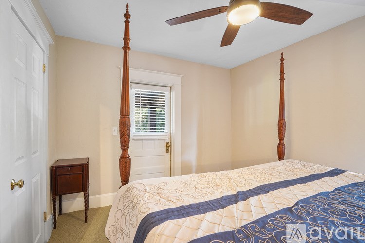 A bedroom with a bed, a table, and a ceiling fan.