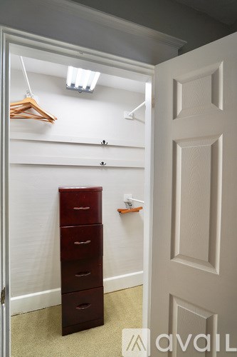 A white door is open to a hallway with a brown dresser and a white wall.