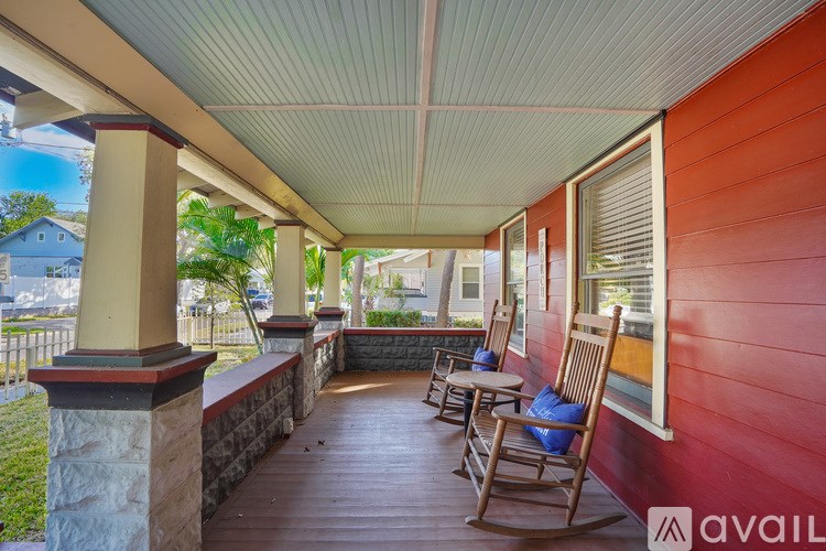 A porch with rocking chairs and a stone pillar.
