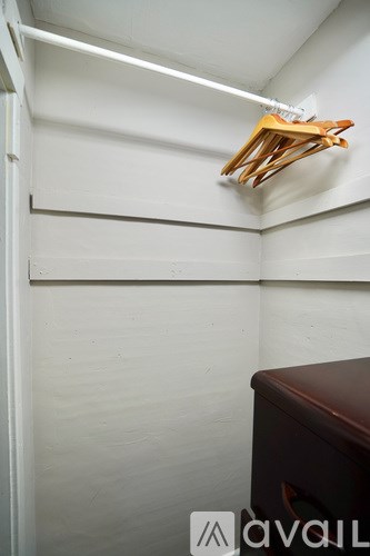 A wooden clothes hanger is hanging on a white wall.