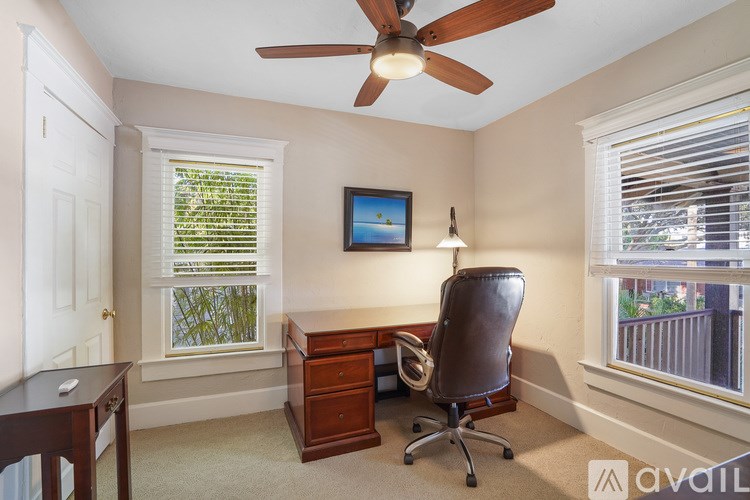 A room with a ceiling fan, a chair, a desk, and a window with blinds.