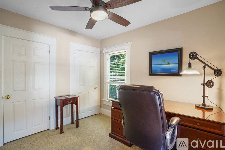 A room with a brown leather chair and a ceiling fan.