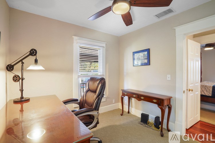 A room with a desk, chair, and a lamp.