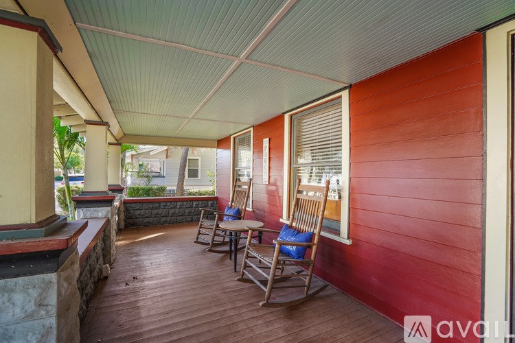 A wooden porch with a rocking chair and a table.