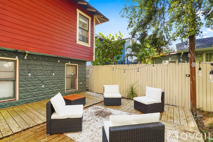 A patio with a red house and white furniture.