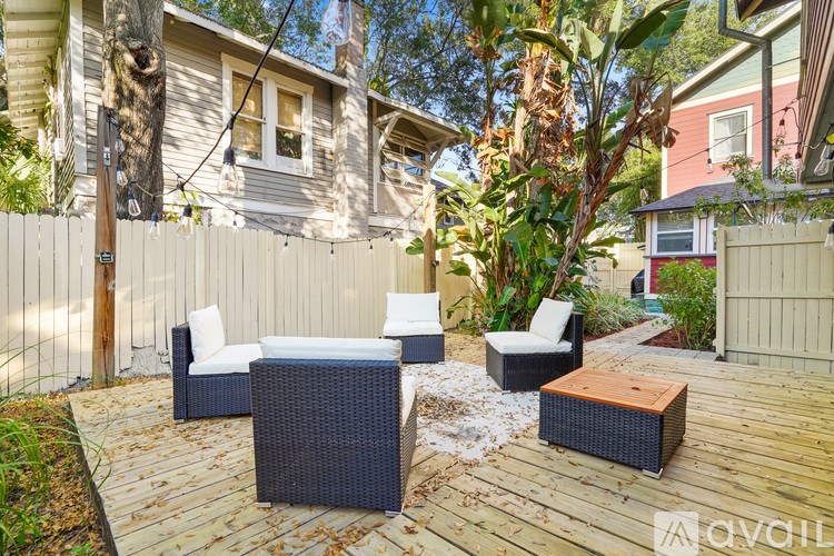 A patio with a white couch and a black chair with a wooden table in the middle.