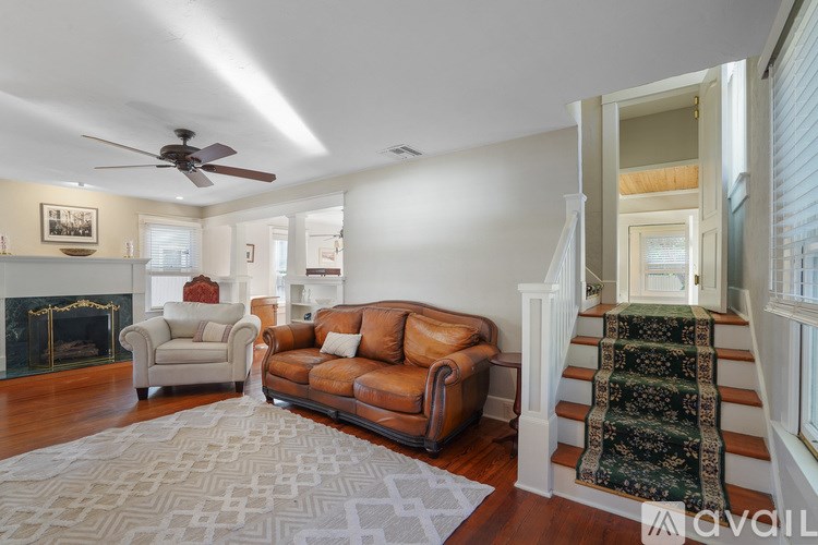A living room with a brown leather couch and a rug.