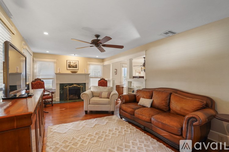 A living room with a brown leather couch and a fireplace.
