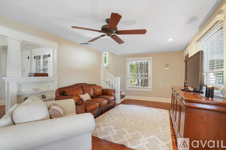 A living room with a brown leather couch and a white armchair.