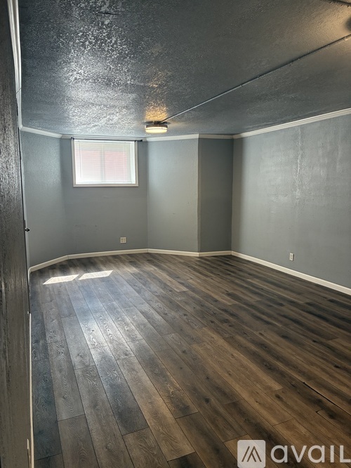 A room with wooden flooring and a window.